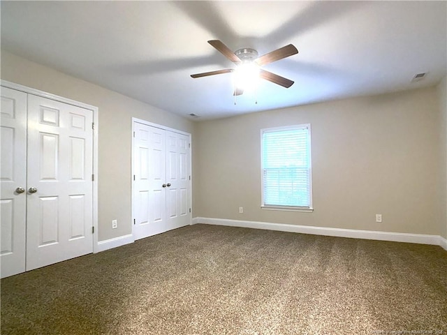 unfurnished bedroom with ceiling fan, carpet flooring, and multiple closets