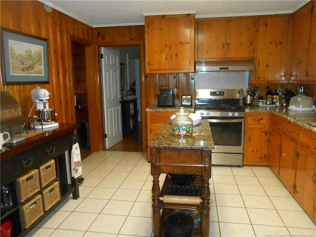 kitchen with a kitchen island, light tile patterned flooring, stainless steel range with gas cooktop, and ornamental molding