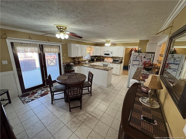 dining room with sink, light tile patterned flooring, crown molding, and a textured ceiling