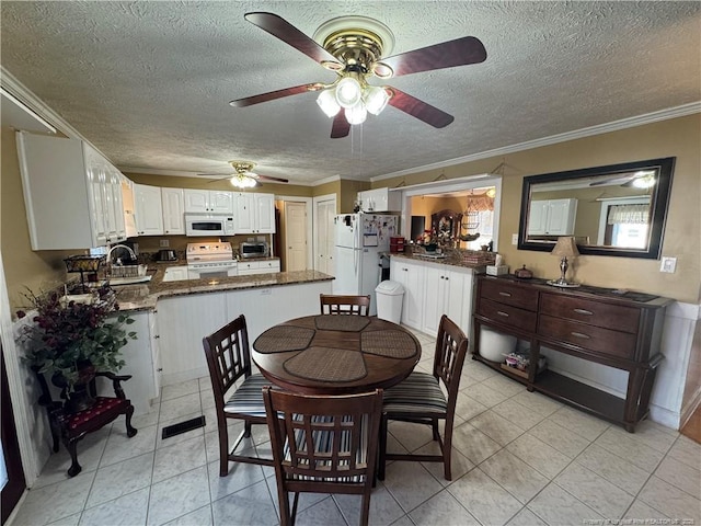 tiled dining room with ceiling fan, sink, a textured ceiling, and ornamental molding