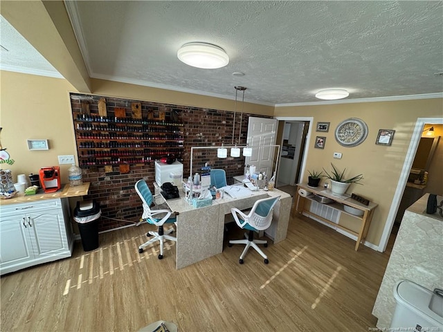 office space featuring built in desk, light wood-type flooring, ornamental molding, and a textured ceiling