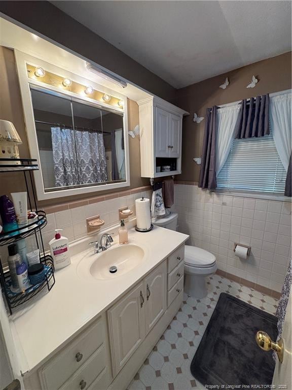 bathroom with tile walls, toilet, and vanity