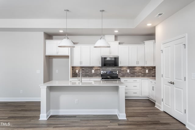 kitchen with range with electric stovetop, white cabinetry, a kitchen island with sink, and pendant lighting