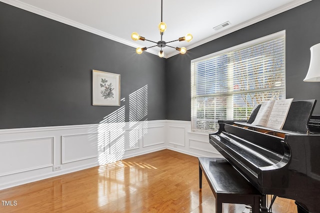 miscellaneous room with hardwood / wood-style floors, crown molding, and an inviting chandelier