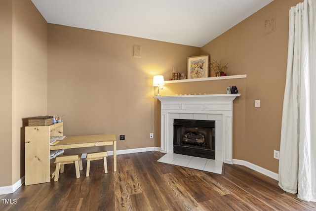 living room with a tiled fireplace, dark hardwood / wood-style floors, and vaulted ceiling