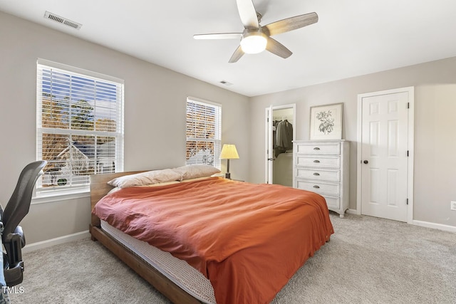 carpeted bedroom featuring ceiling fan, a closet, and a walk in closet