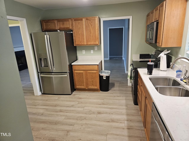 kitchen featuring appliances with stainless steel finishes, light hardwood / wood-style flooring, and sink