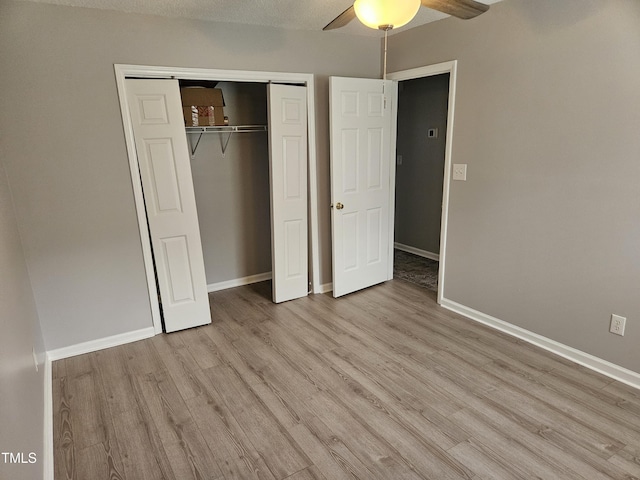 unfurnished bedroom with light wood-type flooring, ceiling fan, and a closet