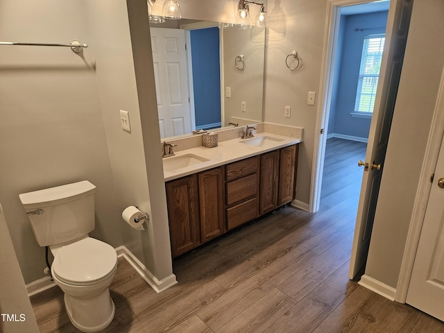 bathroom with toilet, wood-type flooring, and vanity