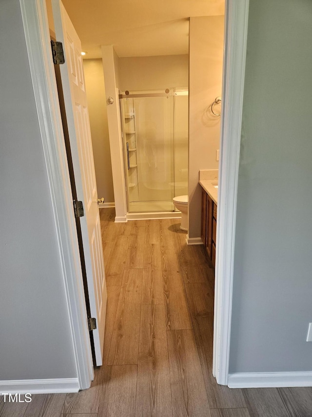 bathroom featuring hardwood / wood-style flooring, an enclosed shower, vanity, and toilet