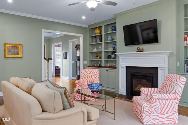 living room with crown molding, ceiling fan, light wood-type flooring, and built in shelves