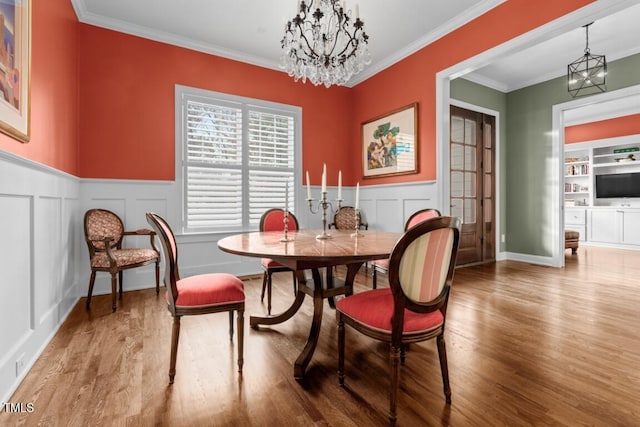 dining area featuring an inviting chandelier, hardwood / wood-style flooring, ornamental molding, and built in shelves