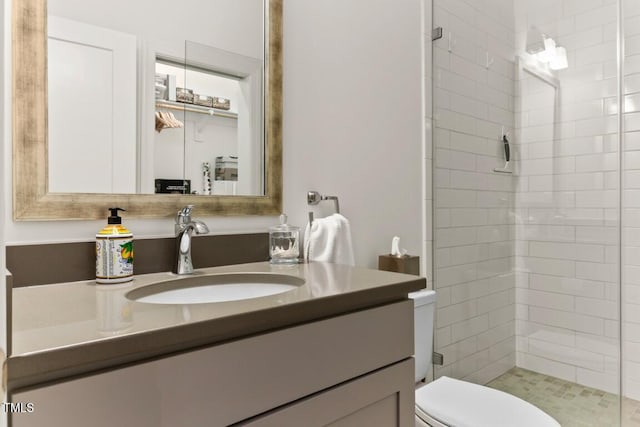 bathroom featuring vanity, a tile shower, and toilet