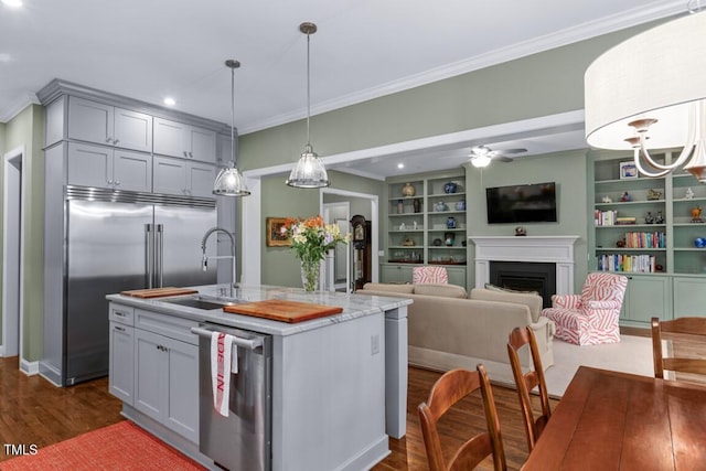 kitchen featuring sink, gray cabinetry, hanging light fixtures, stainless steel appliances, and an island with sink