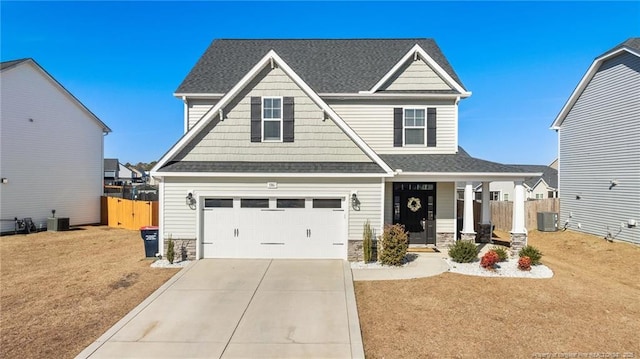 craftsman house with a garage, central AC unit, covered porch, and a front lawn