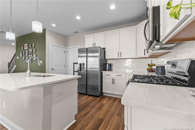 kitchen with appliances with stainless steel finishes, sink, white cabinets, and decorative light fixtures