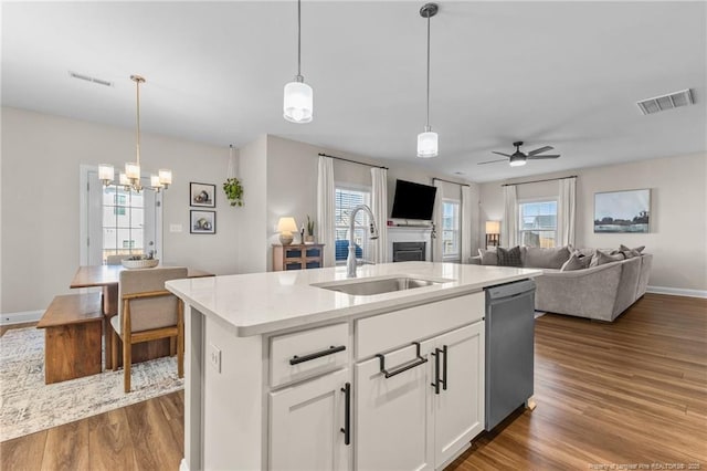 kitchen with sink, decorative light fixtures, a center island with sink, dishwasher, and white cabinets