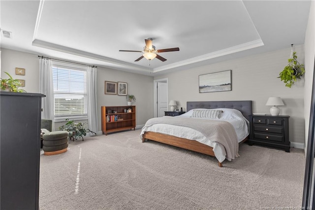 carpeted bedroom featuring a raised ceiling, ornamental molding, and ceiling fan