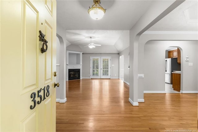 living room featuring light wood-type flooring, ceiling fan, lofted ceiling, and crown molding