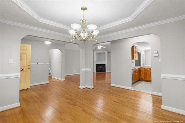 interior space with light wood-type flooring, a tray ceiling, and ornamental molding