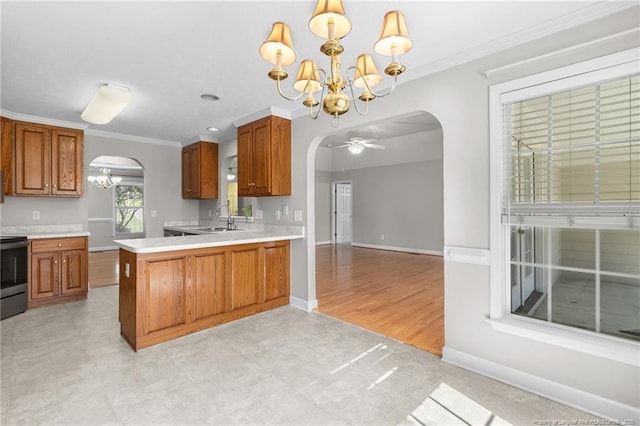 kitchen featuring kitchen peninsula, hanging light fixtures, ornamental molding, ceiling fan with notable chandelier, and sink