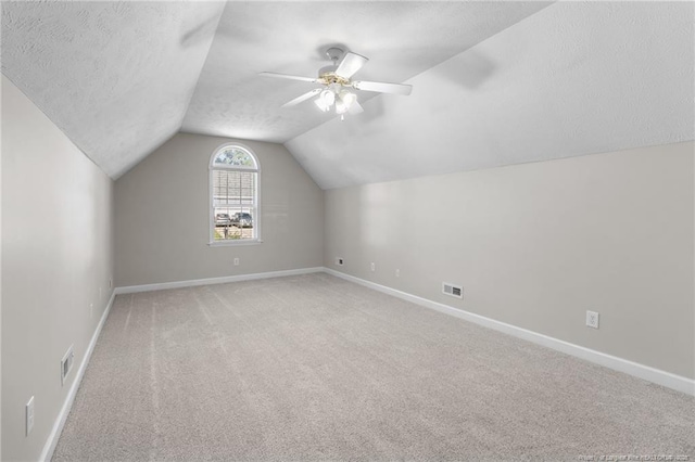 bonus room featuring lofted ceiling, ceiling fan, carpet, and a textured ceiling