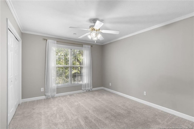 carpeted empty room with ceiling fan and ornamental molding