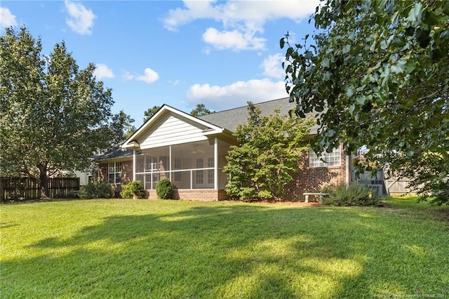 rear view of house with ceiling fan, a yard, and a sunroom