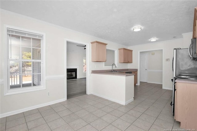 kitchen featuring kitchen peninsula, appliances with stainless steel finishes, light brown cabinets, a textured ceiling, and sink