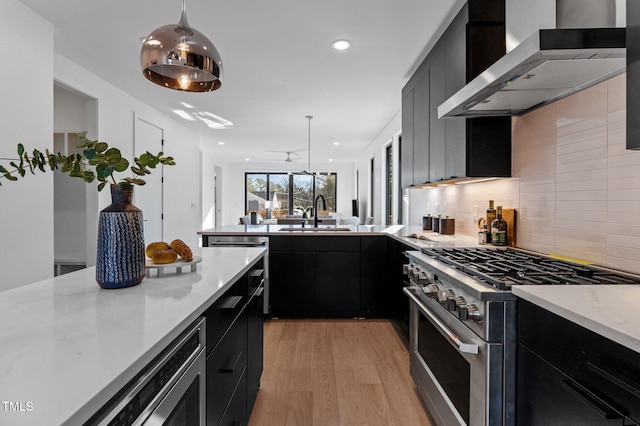 808 Culpepper Ln, Raleigh, NC 27610 - kitchen with pendant lighting, sink, stainless steel appliances, wall chimney exhaust hood, and light wood-type flooring