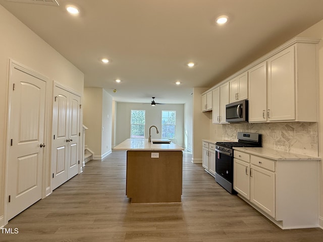 kitchen with appliances with stainless steel finishes, a sink, white cabinetry, and decorative backsplash