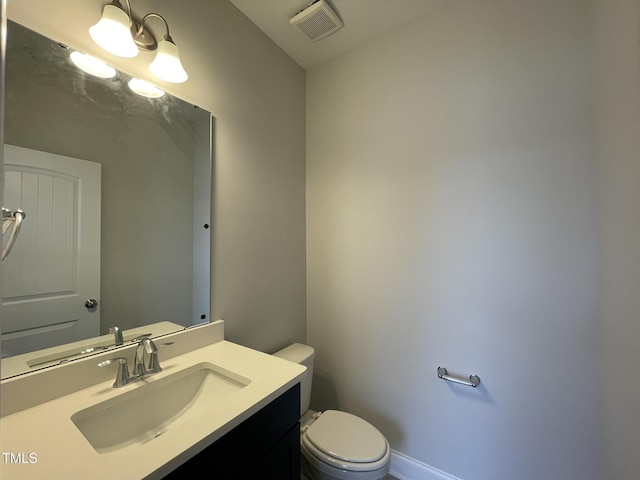 half bath featuring visible vents, baseboards, toilet, and vanity