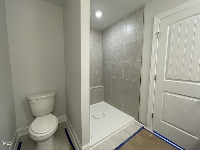 bathroom featuring baseboards, toilet, and a shower stall