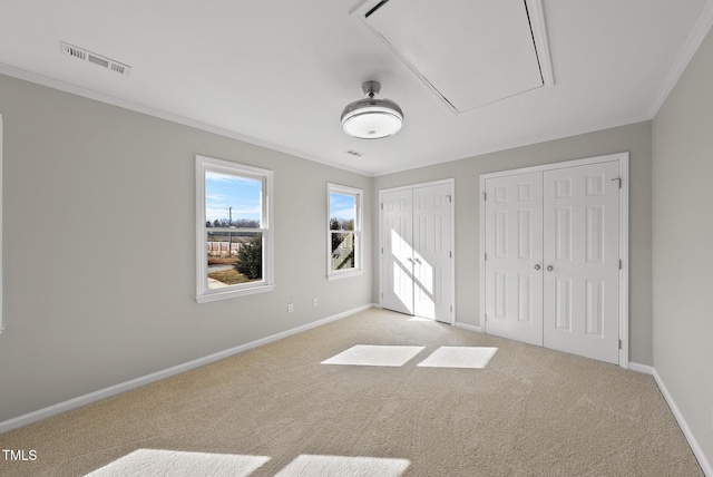 unfurnished bedroom with light colored carpet, ornamental molding, and two closets