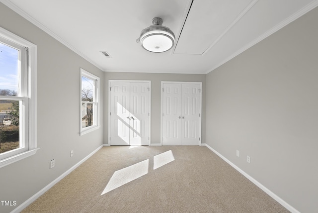 unfurnished bedroom with light carpet, two closets, and crown molding