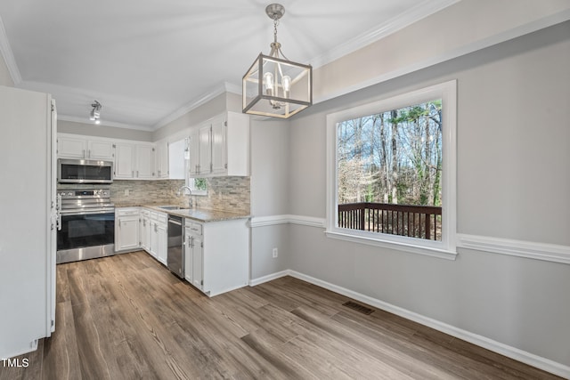 kitchen with stainless steel appliances, sink, pendant lighting, and white cabinets