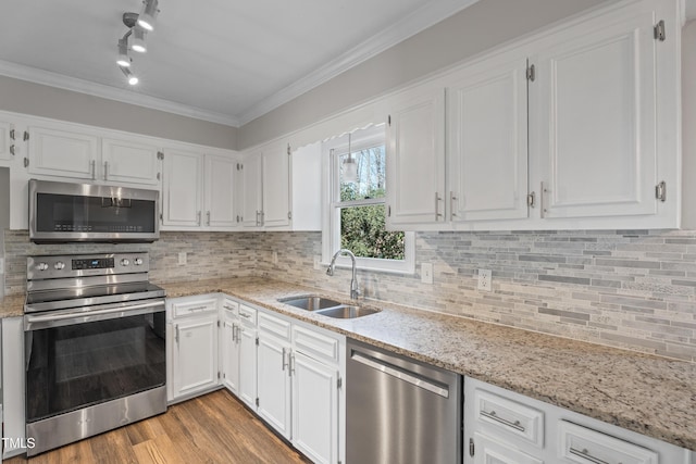 kitchen with appliances with stainless steel finishes, tasteful backsplash, white cabinetry, sink, and ornamental molding