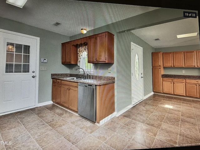 kitchen with dark countertops, dishwashing machine, baseboards, and a sink