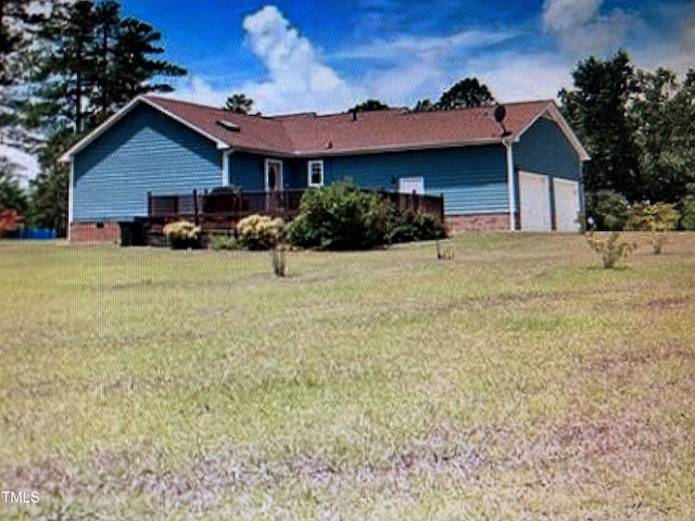 rear view of property with a garage and a lawn