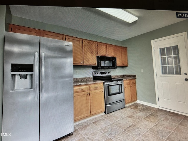 kitchen with appliances with stainless steel finishes, brown cabinetry, and baseboards