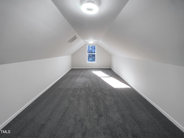 additional living space with vaulted ceiling and dark colored carpet