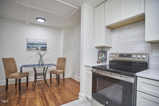 kitchen with dark wood-type flooring, backsplash, white cabinets, and electric stove