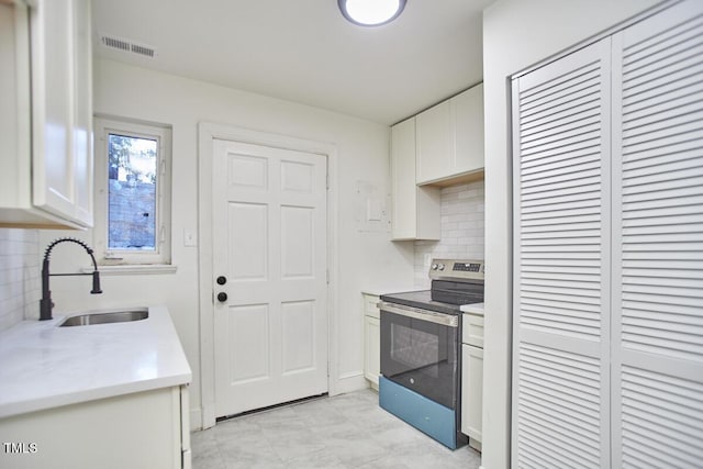 kitchen featuring electric stove, sink, tasteful backsplash, and white cabinetry