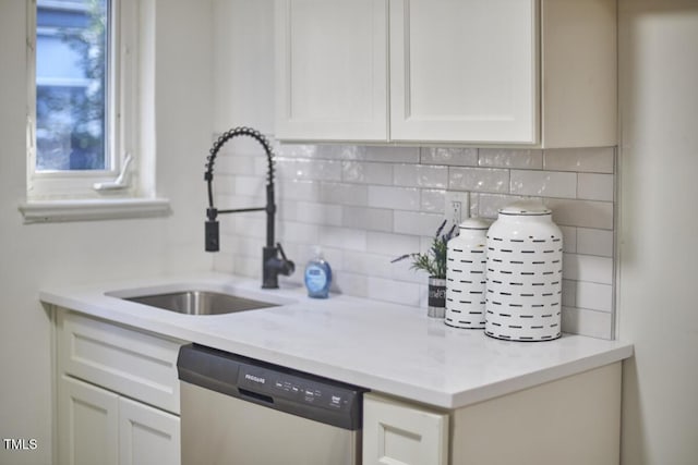 kitchen featuring stainless steel dishwasher, white cabinets, sink, and tasteful backsplash