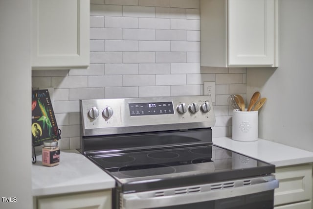 kitchen with tasteful backsplash, white cabinets, and stainless steel electric range oven