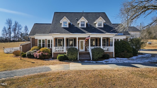 cape cod house featuring a front lawn and a porch