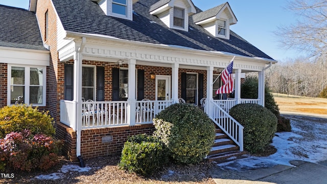 cape cod home featuring covered porch