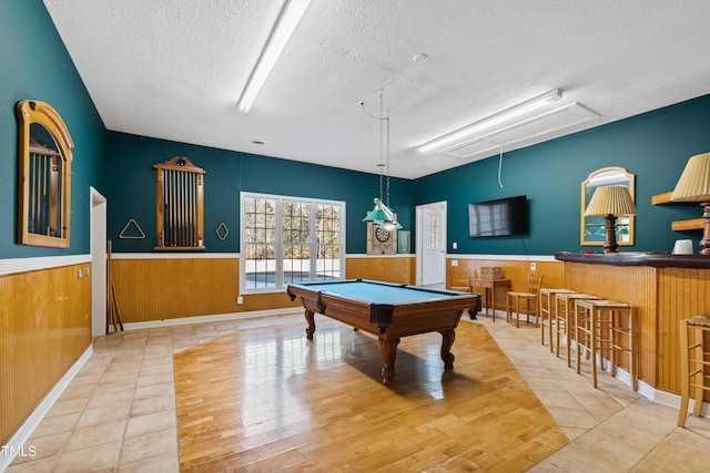 game room with tile patterned flooring, billiards, a textured ceiling, and wood walls