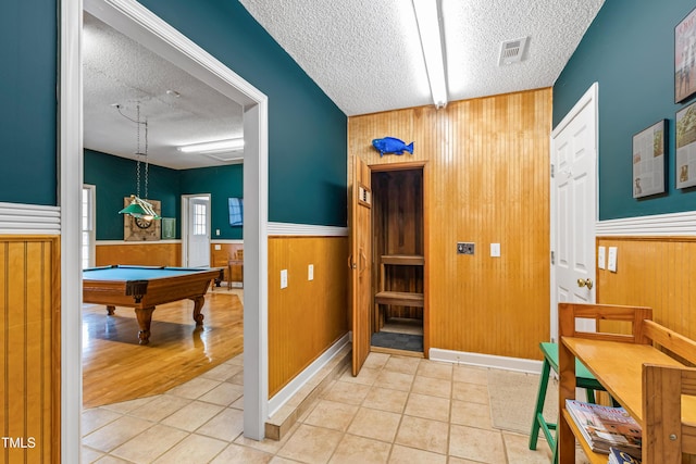 interior space featuring tile patterned floors, a textured ceiling, and wood walls