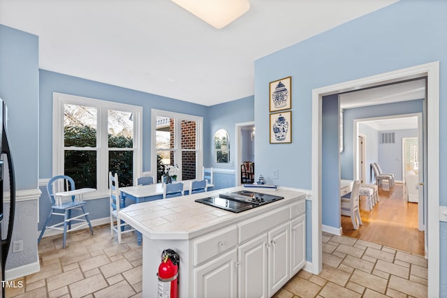 kitchen featuring white cabinetry, black electric stovetop, tile countertops, and kitchen peninsula